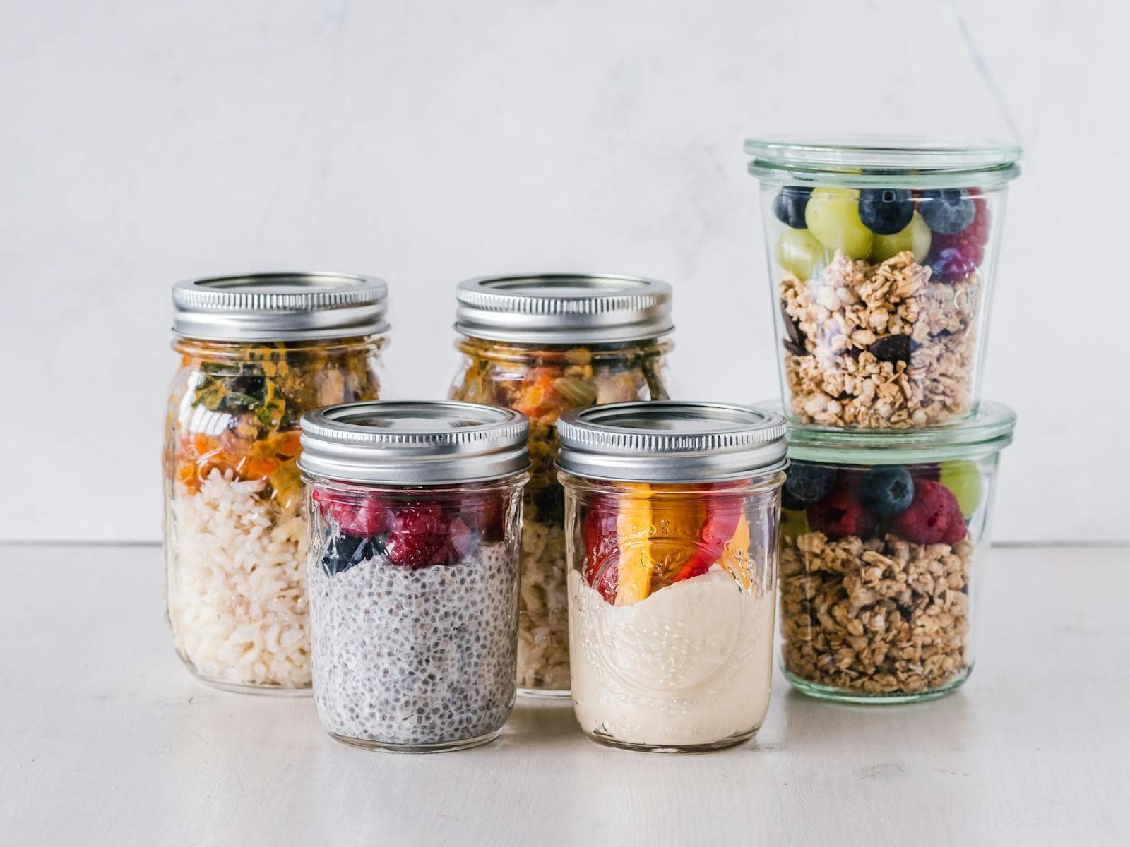 Indigestion, guts, bloating, gas, acid reflux, health, functional medicine, wellness, mind gut connection, Close-up of healthy food jars containing granola, fruits, and yogurt.