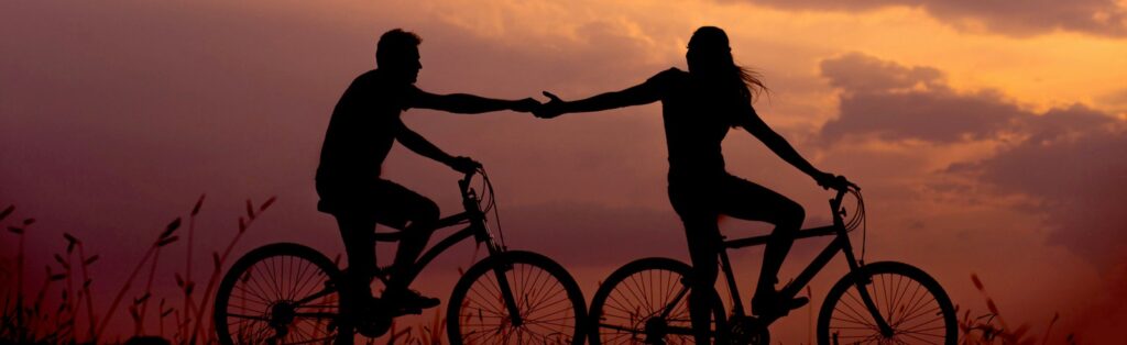 woman on bike reaching for man's hand behind her also on bike